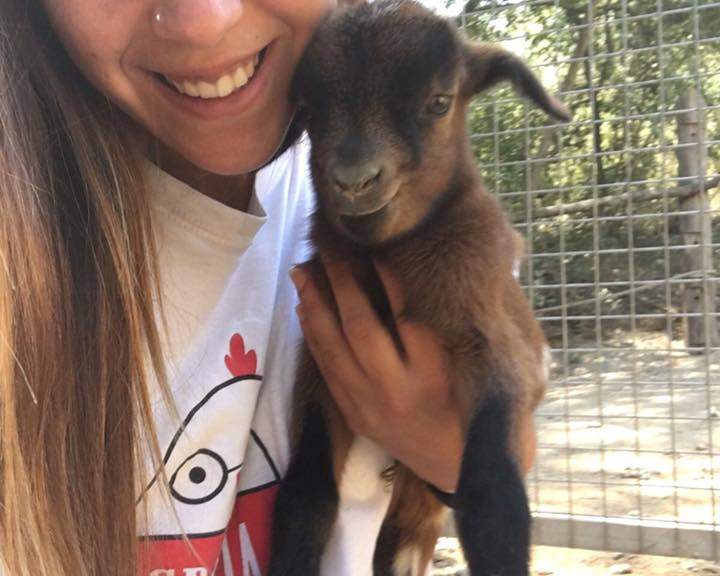Noia somrient sostenint en braços una cabreta negra i marró