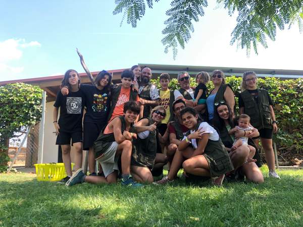 Grup de voluntaris i famílies posant somrients a la gespa davant d'una casa